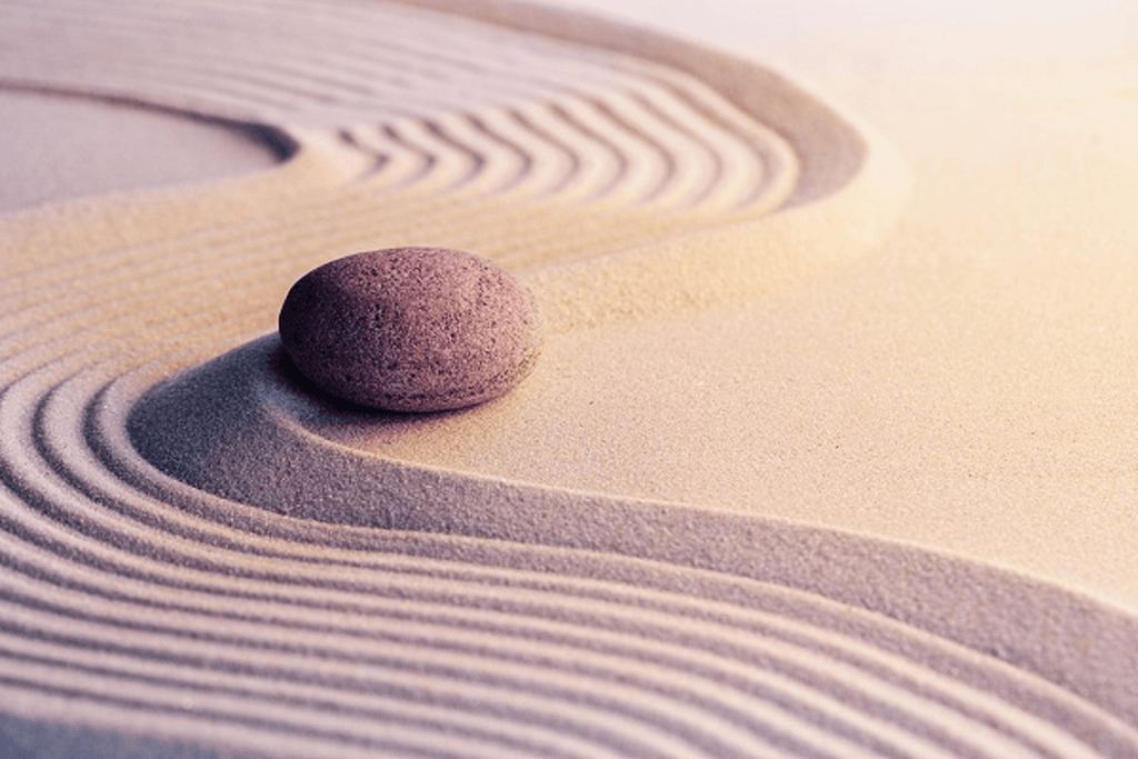 Zen garden in sand with single stone and swirls in sand